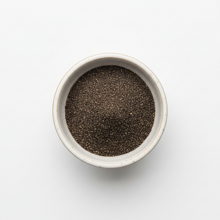 Small bowl filled with dark chia seeds on a light gray background