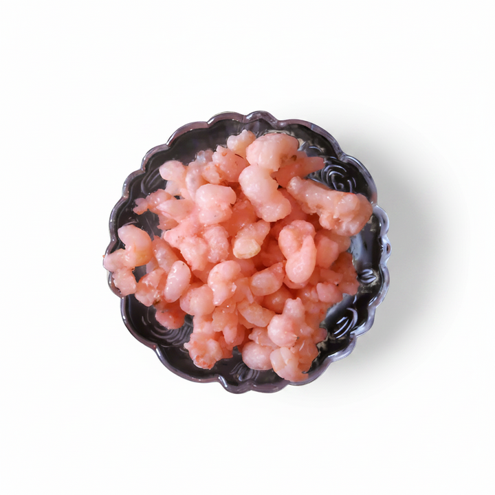 A bowl of cooked shrimps on a white background.