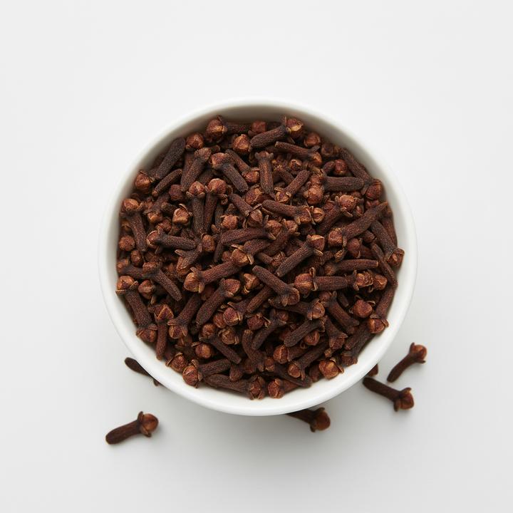 whole cloves in a bowl with a plain background